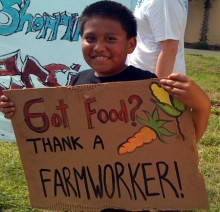 A farm worker supporter holding a sign that says "Got Food? Thank a Farmworker!
