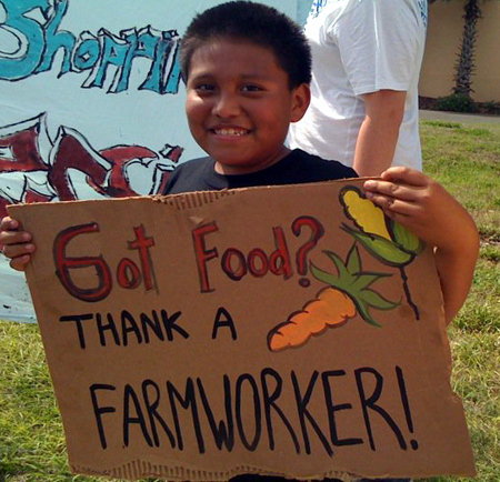A farm worker supporter holding a sign that says "Got Food? Thank a Farmworker!